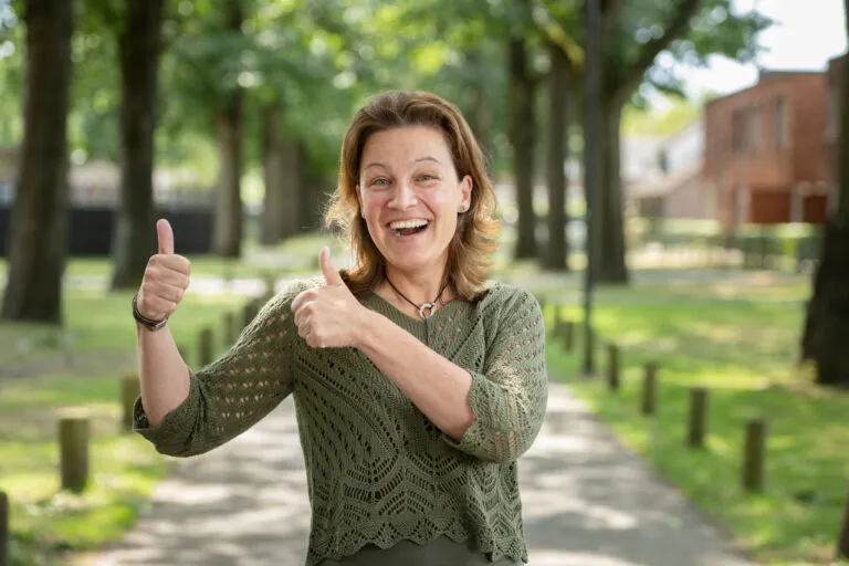 Onboarding bij Amarant. Medewerker lacht in de camera en steekt beide duimen omhoog