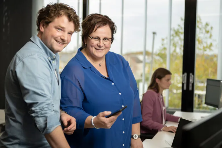 Ondersteuning en onboarding nieuwe medewerker, collega legt uit op de telefoon hoe de Amarant app werkt aan de andere collega