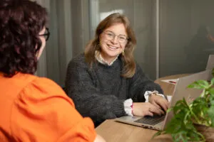 infomarkt amarant, medewerker achter laptop in gesprek met collega.