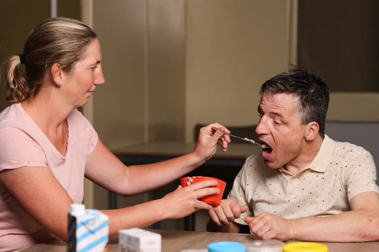 Doelgroep LVB-EMB, Zorgmedewerker / begeleider voert eten met lepel aan cliënt