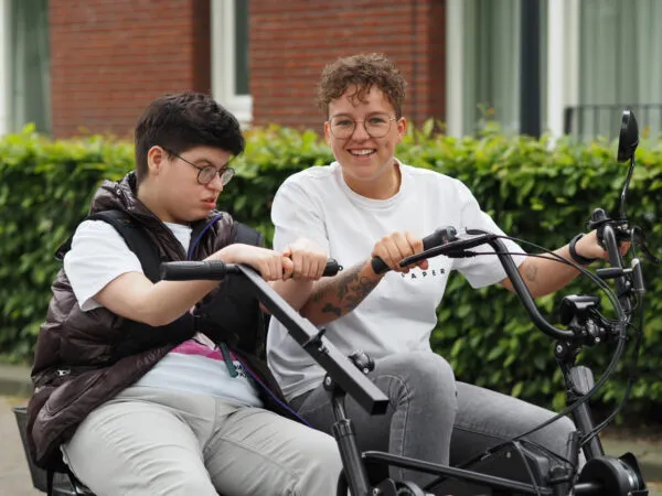 Doelgroepen Amarant, begeleider fietst met cliënt. Duofiets,.