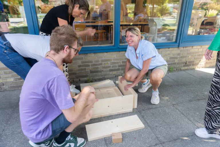 Vrijwilligers extern bedrijf zet tafel in elkaar, samen lachen