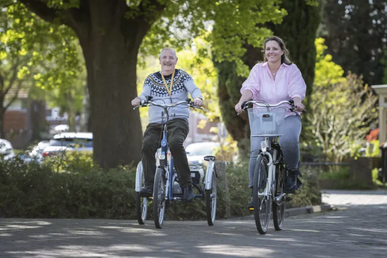 Doelgroep ouderen. zorgprofessional fietst met cliënt.