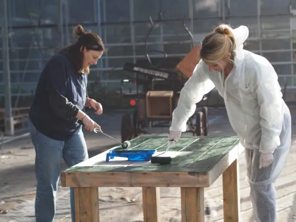 Bedrijven die vrijwilligerswerk komen doen, zoals klusjes. 2 dames schilderen tafel