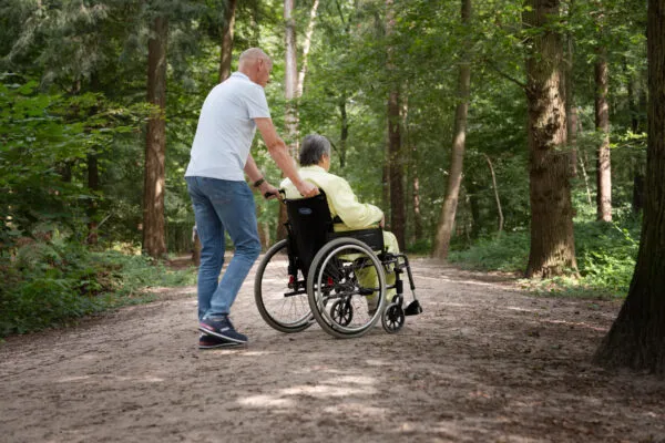 Vrijwilliger bij Amarant wandelt met cliënt in rolstoel